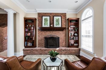A living room with a brick fireplace and leather furniture